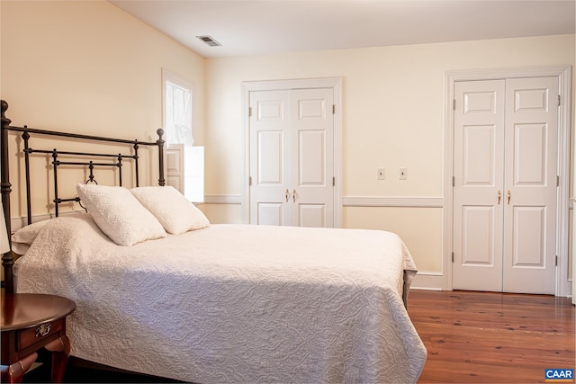 bedroom featuring two closets and dark hardwood / wood-style flooring