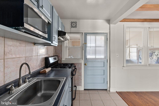 kitchen featuring beam ceiling, stainless steel appliances, sink, ventilation hood, and light tile patterned floors