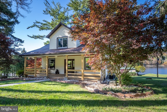 farmhouse inspired home with a water view, a porch, and a front lawn