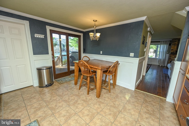 tiled dining area featuring ornamental molding and a notable chandelier