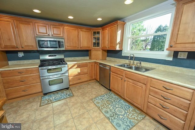 kitchen with appliances with stainless steel finishes, sink, and light tile patterned floors