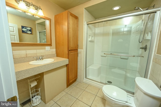 bathroom with tile patterned floors, toilet, a shower with shower door, and vanity