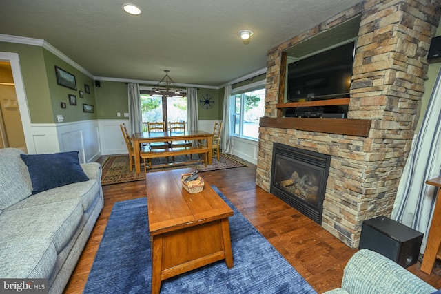 living room with crown molding, dark hardwood / wood-style floors, and a stone fireplace