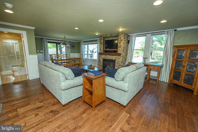 living room featuring hardwood / wood-style flooring, ornamental molding, a fireplace, and a notable chandelier