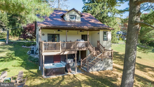 back of property featuring a hot tub, a yard, a deck, and ceiling fan