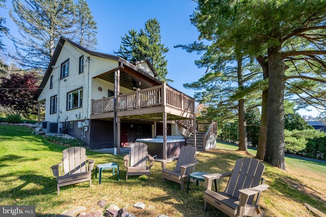 back of house featuring cooling unit, a hot tub, a deck, and a lawn