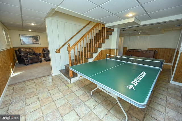 recreation room with a drop ceiling and wooden walls