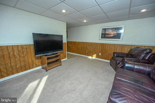 living room with carpet, a paneled ceiling, and wooden walls