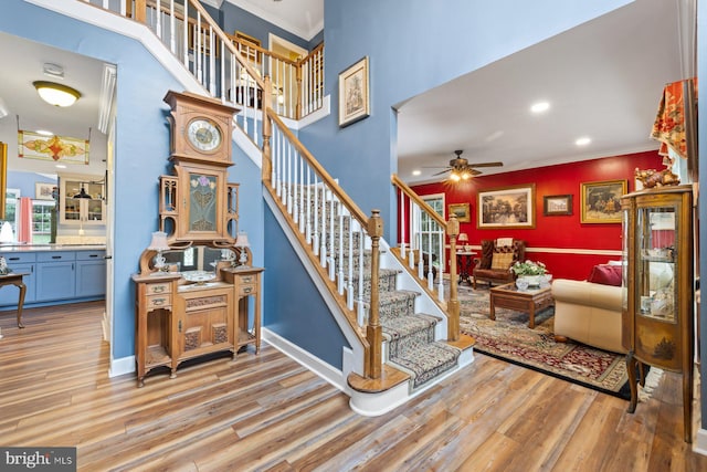 stairs featuring ornamental molding, hardwood / wood-style floors, and ceiling fan