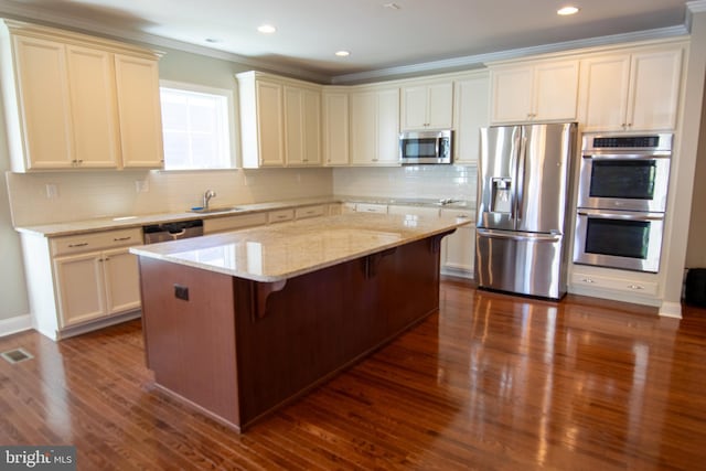 kitchen with a kitchen island, dark hardwood / wood-style floors, stainless steel appliances, light stone countertops, and a kitchen bar