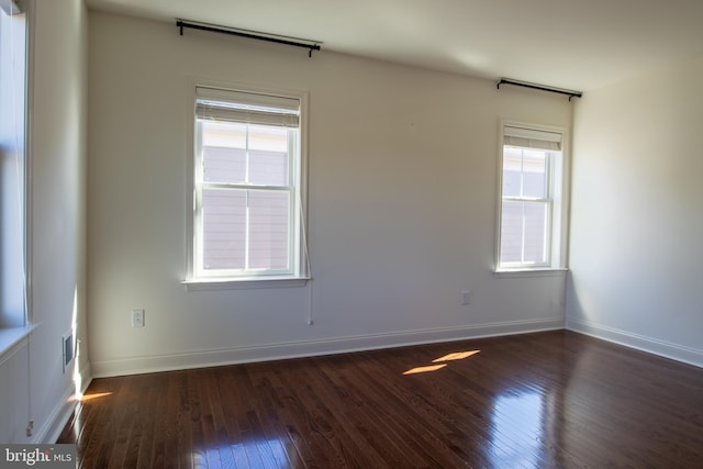 spare room with dark wood-type flooring and a healthy amount of sunlight