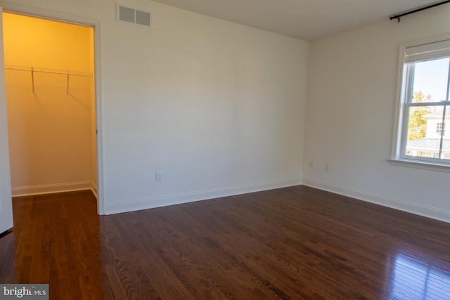 interior space featuring a closet, a walk in closet, and dark hardwood / wood-style floors