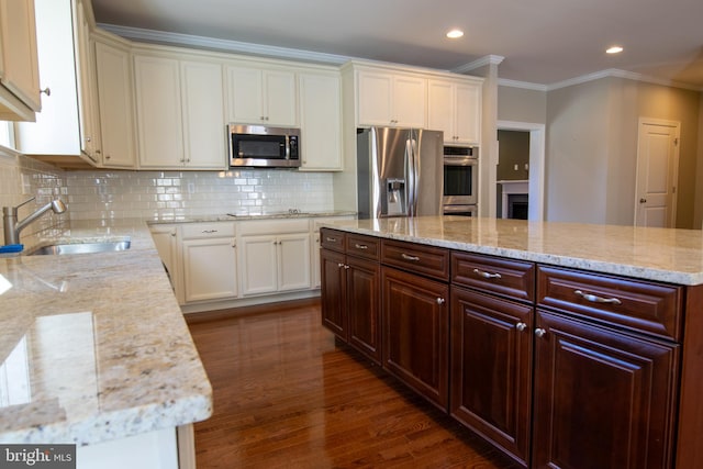 kitchen featuring dark wood-type flooring, stainless steel appliances, sink, a center island, and light stone counters