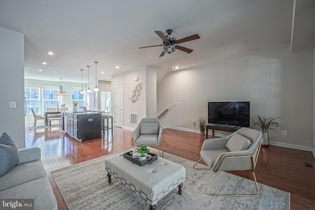 living room with sink, hardwood / wood-style floors, and ceiling fan with notable chandelier