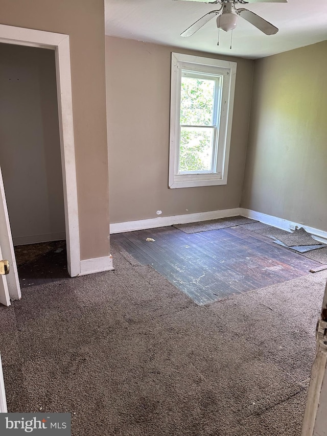 spare room featuring ceiling fan and dark carpet