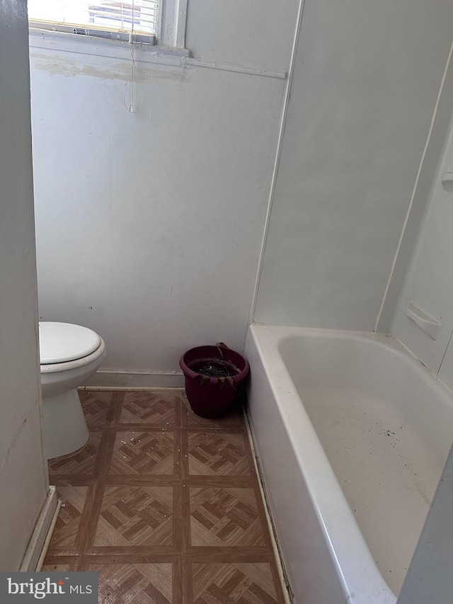 bathroom featuring a bathtub, toilet, and parquet floors