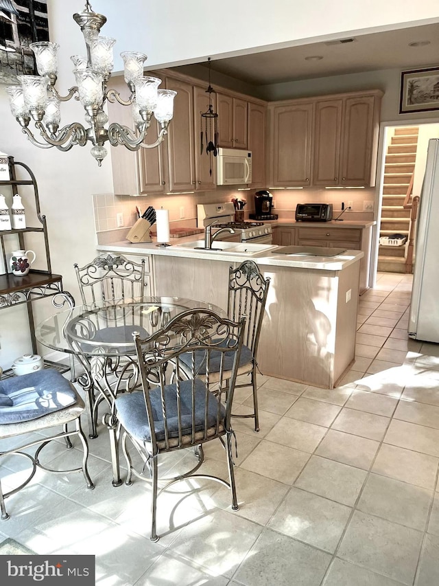 kitchen with kitchen peninsula, light tile patterned flooring, a chandelier, and white appliances