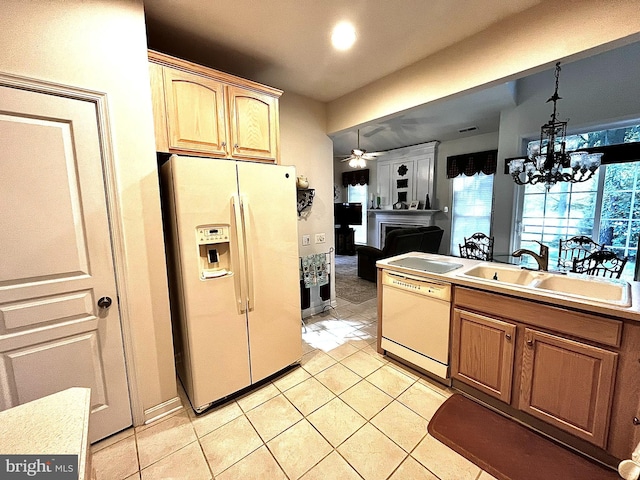 kitchen featuring sink, hanging light fixtures, white appliances, light tile patterned floors, and ceiling fan with notable chandelier