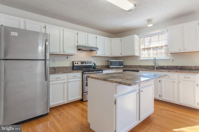 kitchen with appliances with stainless steel finishes, light wood-type flooring, a center island, and white cabinets