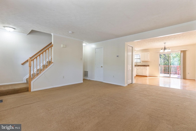 unfurnished living room featuring ornamental molding, light carpet, a notable chandelier, and a textured ceiling