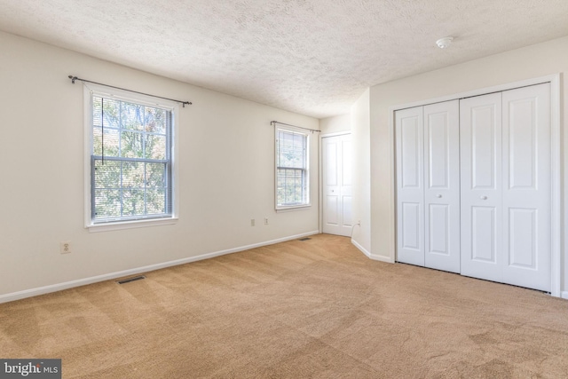 unfurnished bedroom featuring light carpet and multiple windows