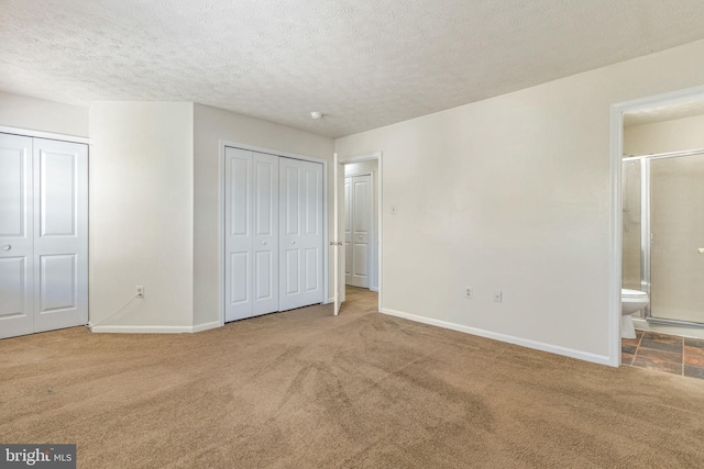 unfurnished bedroom with connected bathroom, carpet, and a textured ceiling