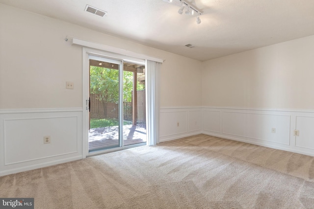 empty room featuring track lighting and light colored carpet