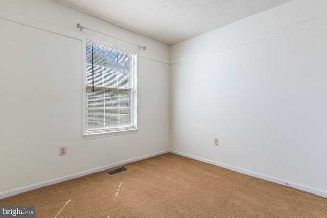 carpeted empty room featuring a textured ceiling