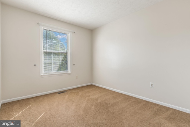 carpeted empty room with a textured ceiling