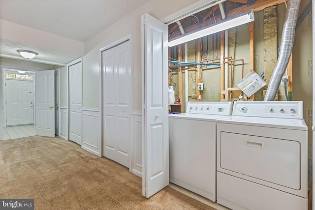 laundry area with light carpet, a textured ceiling, and washing machine and dryer