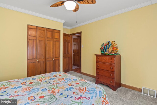 carpeted bedroom featuring crown molding, a closet, and ceiling fan