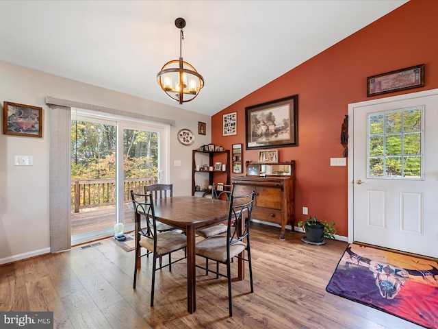 dining space with light hardwood / wood-style floors, a chandelier, and vaulted ceiling