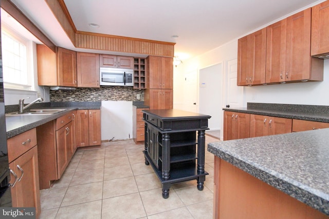 kitchen featuring light tile patterned flooring, a center island, decorative backsplash, and sink