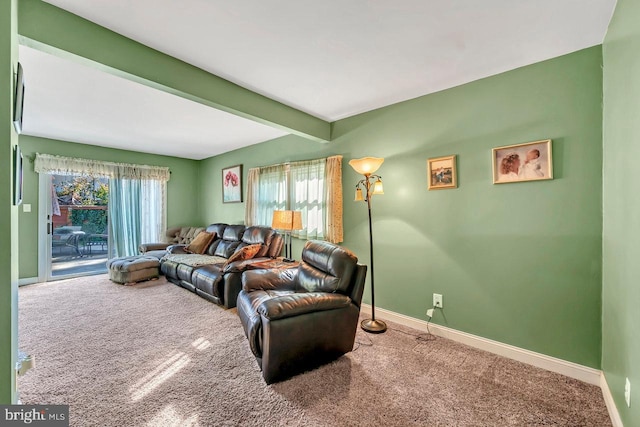 living room featuring beamed ceiling, carpet, and a healthy amount of sunlight