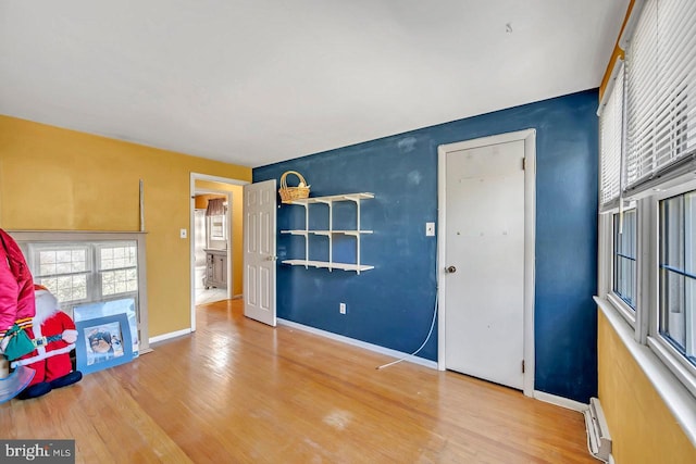 interior space with a baseboard heating unit and hardwood / wood-style flooring