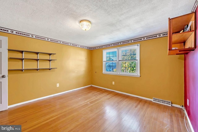 spare room with hardwood / wood-style flooring and a textured ceiling