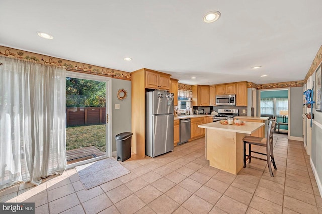 kitchen featuring a breakfast bar area, a center island, stainless steel appliances, and a healthy amount of sunlight