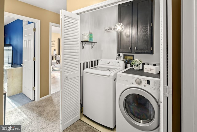 laundry area featuring light carpet, washer and clothes dryer, and cabinets