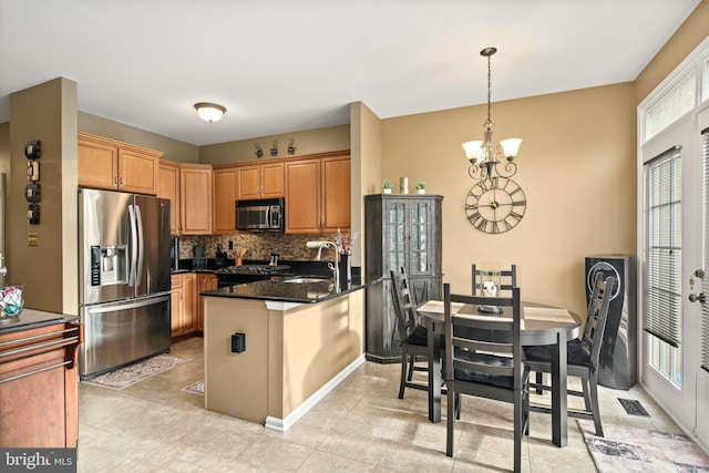 kitchen with appliances with stainless steel finishes, kitchen peninsula, dark stone counters, and plenty of natural light