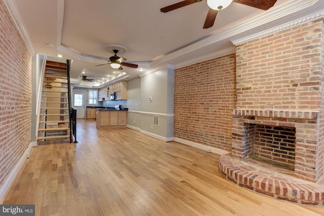 unfurnished living room featuring brick wall, crown molding, a fireplace, and light wood-type flooring