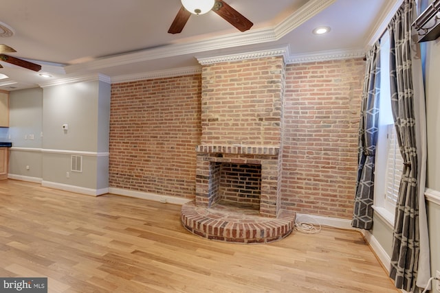 unfurnished living room with light hardwood / wood-style floors, brick wall, ornamental molding, and a fireplace