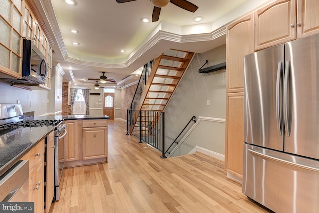 kitchen featuring appliances with stainless steel finishes, light brown cabinetry, light hardwood / wood-style floors, dark stone countertops, and ornamental molding