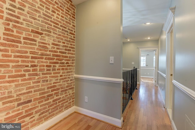 corridor with brick wall and light wood-type flooring