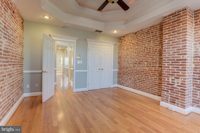 unfurnished room featuring ornamental molding, brick wall, and light wood-type flooring