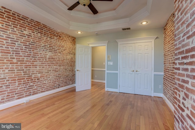 unfurnished bedroom with brick wall, crown molding, light hardwood / wood-style flooring, and ceiling fan