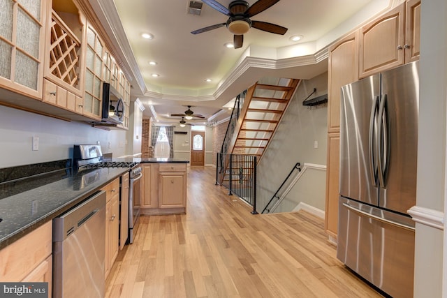 kitchen featuring light brown cabinets, dark stone counters, ornamental molding, light hardwood / wood-style floors, and stainless steel appliances