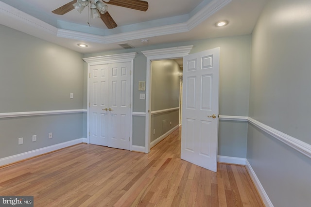 unfurnished bedroom with a closet, ceiling fan, light hardwood / wood-style floors, and a raised ceiling