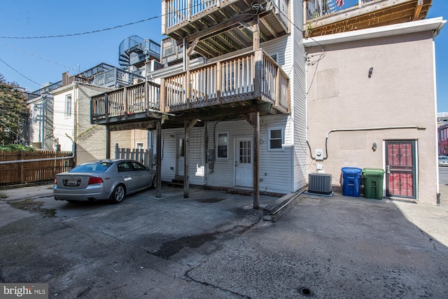 back of property with a deck and central AC