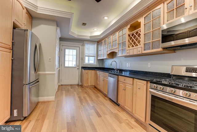 kitchen with light brown cabinets, stainless steel appliances, dark stone countertops, sink, and light hardwood / wood-style floors