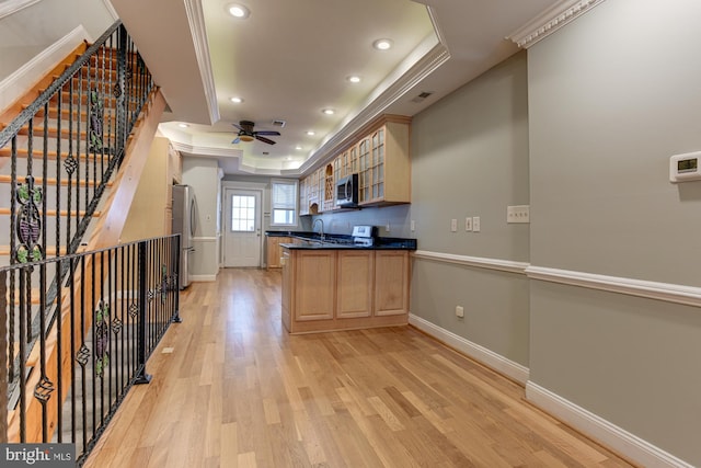 kitchen with stainless steel appliances, ornamental molding, sink, light hardwood / wood-style floors, and ceiling fan